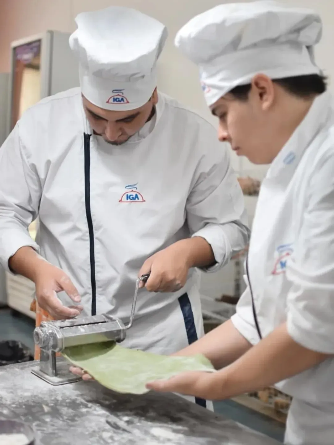 Dos alumnos estirando masa en la mesada