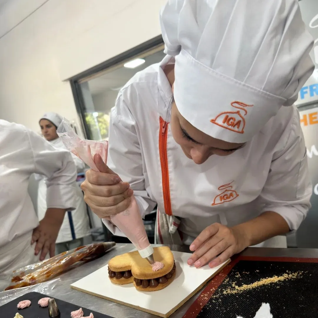 Alumna decorando un postre con manga pastelera