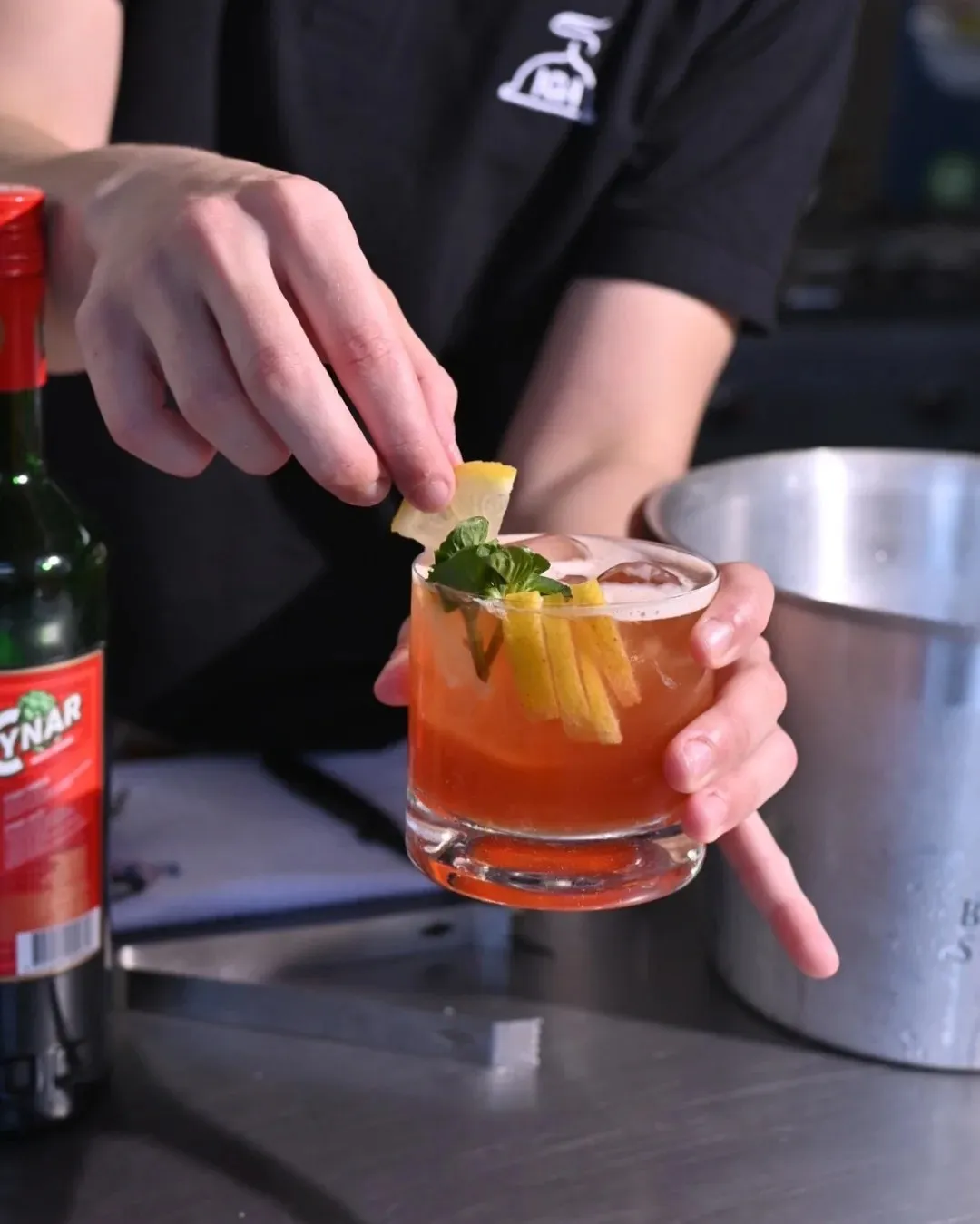 Manos armando un trago con frutas y hielo