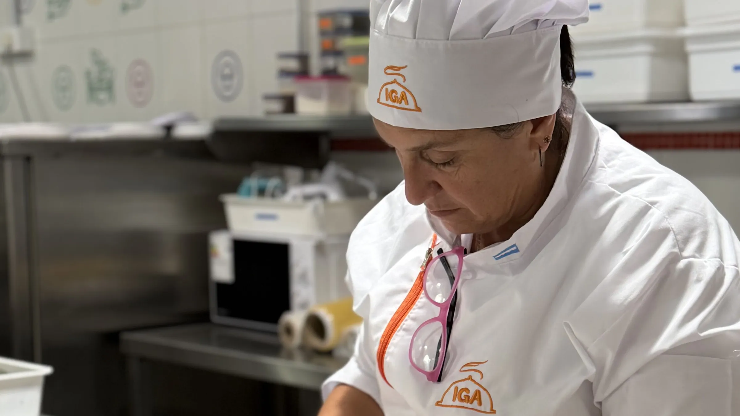 Cocinera con uniforme de IGA trabajando concentrada en una cocina profesional